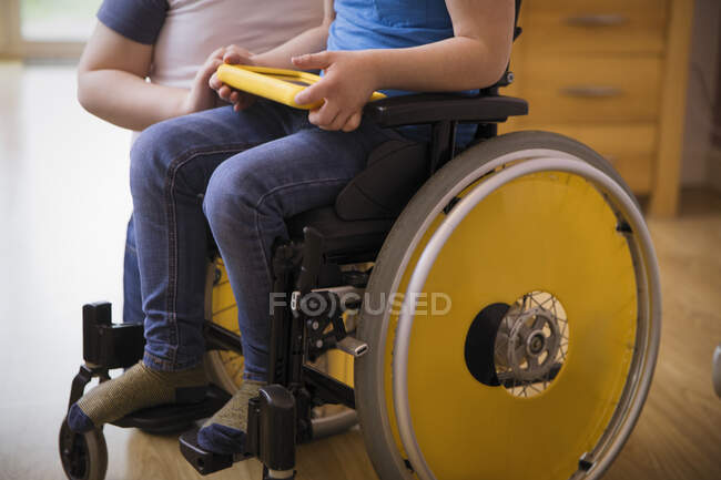 Garçon en fauteuil roulant en utilisant une tablette numérique — Photo de stock