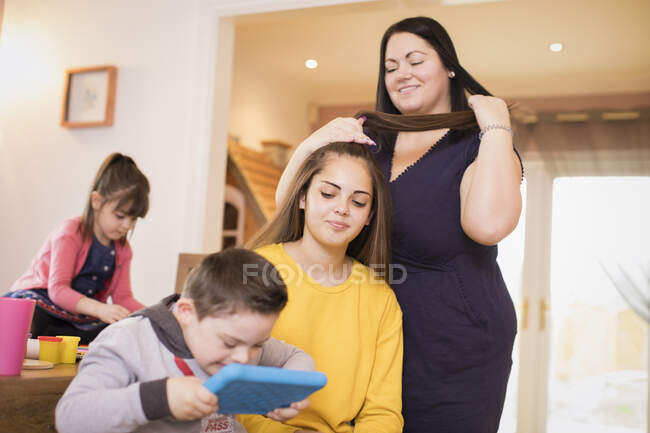 Família fixando cabelo e usando tablet digital na sala de jantar — Fotografia de Stock