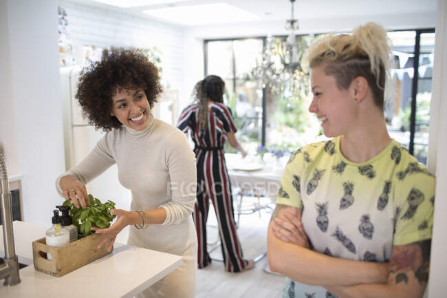 Mujeres jóvenes felices hablando en cocina - foto de stock