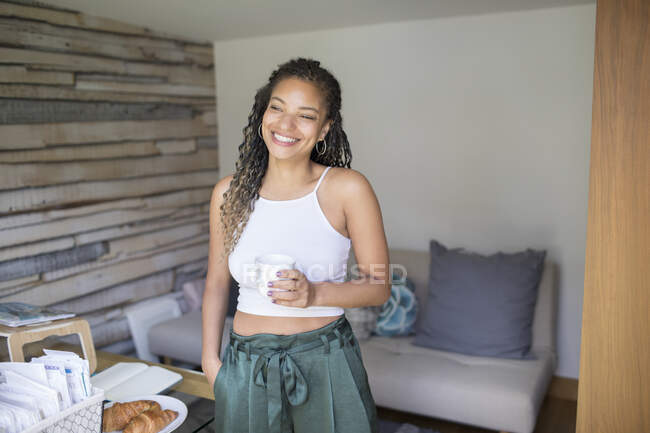 Портрет счастливой молодой женщины, пьющей кофе в домашнем офисе — стоковое фото
