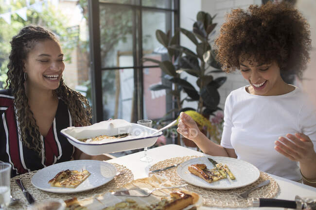 Glückliche junge Frauen beim Mittagessen am Esstisch — Stockfoto