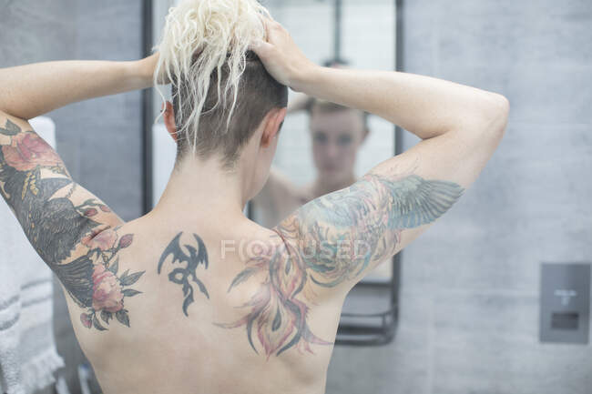Donna con schienale tatuato allo specchio da bagno — Foto stock