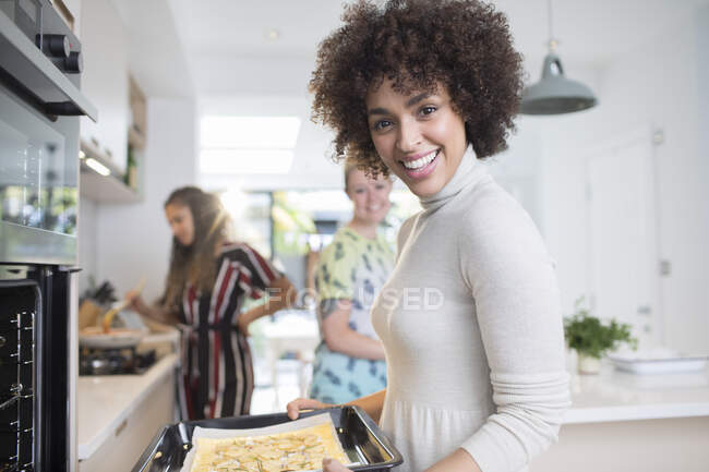 Retrato feliz mujer joven cocinando con amigos en la cocina. - foto de stock