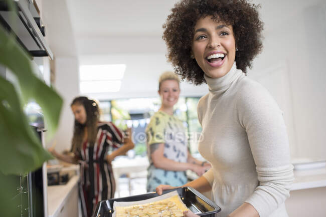 Glückliche junge Frau kocht mit Freunden in Küche — Stockfoto