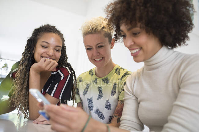 Молоді жінки друзі використовують смартфон — стокове фото