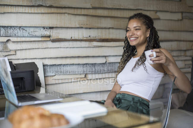 Feliz jovem mulher beber café no laptop em casa escritório — Fotografia de Stock