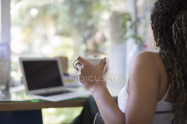Mulher nova bebendo chá no laptop em casa escritório — Fotografia de Stock