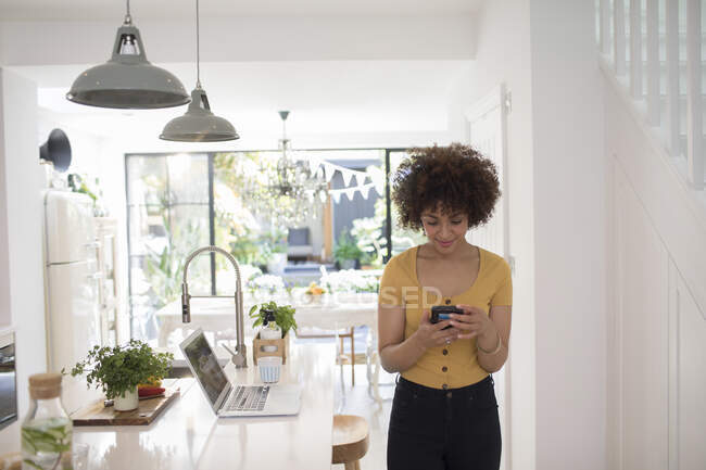 Jovem freelancer feminino usando smartphone na cozinha — Fotografia de Stock