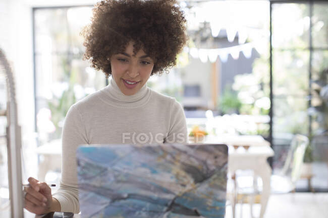 Focused young female freelancer working at laptop in kitchen — Stock Photo