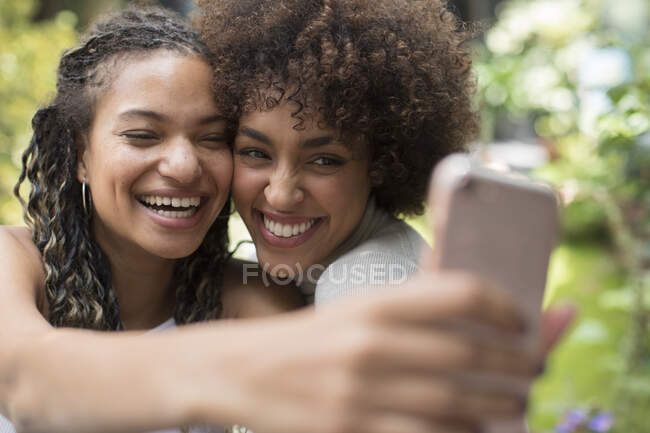 Happy playful young women friends taking selfie with camera phone — Stock Photo