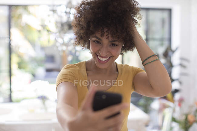 Впевнена, що посміхається молодій жінці, яка робить вибір за допомогою мобільного телефону. — стокове фото