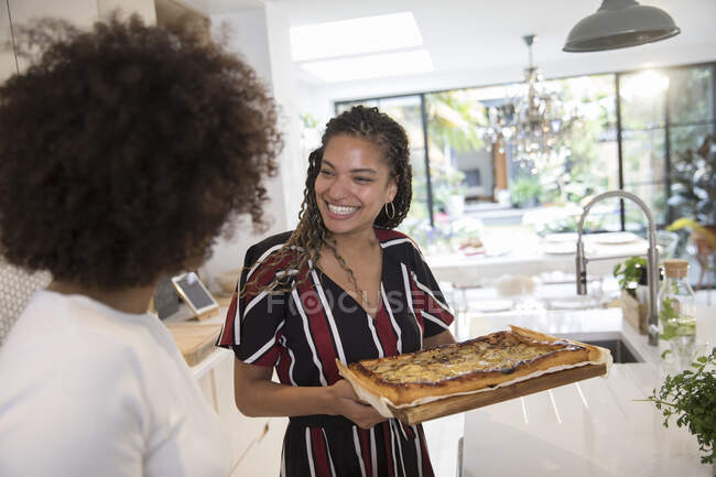 Happy young women friends with homemade pizza in kitchen — Stock Photo