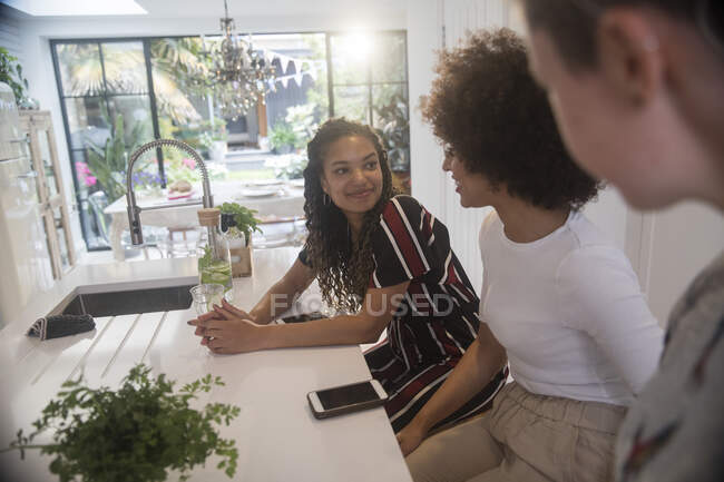 Young women friends with smart phones talking in kitchen — Stock Photo