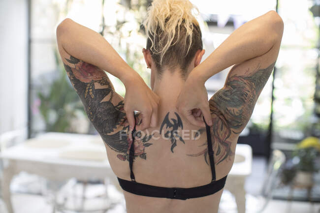 Woman with tattooed shoulders adjusting bra straps — Stock Photo
