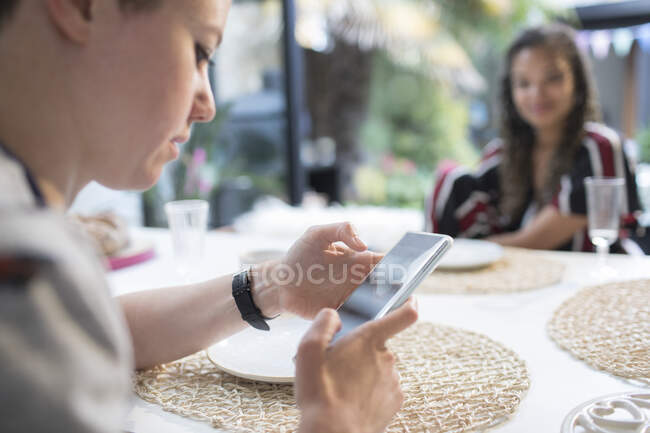 Mulher nova usando telefone inteligente na mesa de jantar — Fotografia de Stock