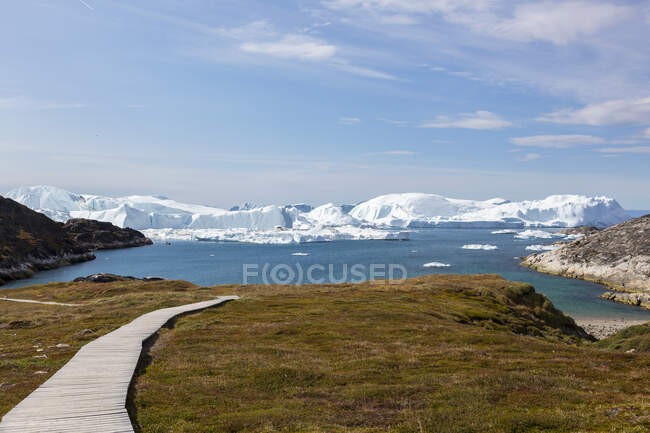 Сонячний пішохідний шлях веде до пляжу з видом на айсберги Гренландія. — стокове фото