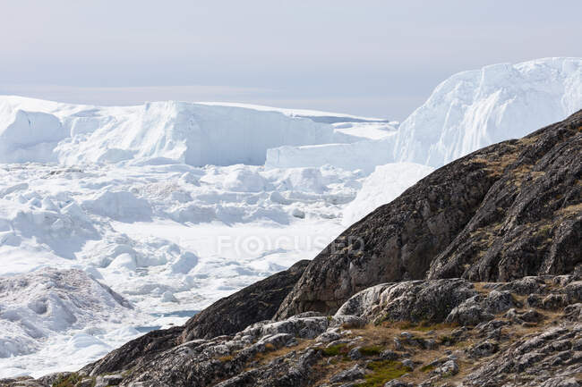 Los icebergs polares más allá de las rocas Groenlandia - foto de stock