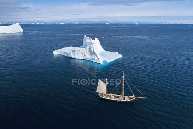 Nave che naviga oltre iceberg sulla soleggiata Groenlandia blu dell'Oceano Atlantico — Foto stock