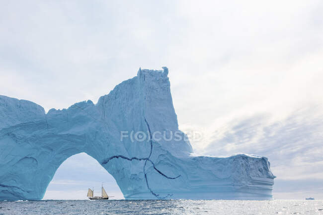 Ship sailing behind majestic iceberg arch on Atlantic Ocean Greenland — Stock Photo