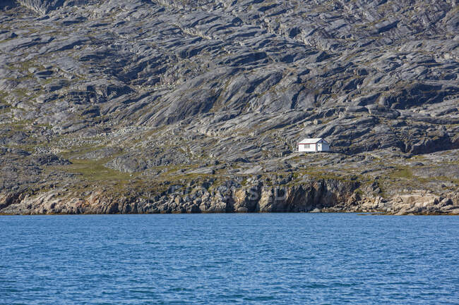 Casa en la soleada costa remota escarpada Disko Bay West Groenlandia - foto de stock