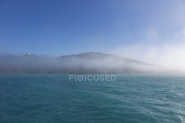 Niebla rompiendo montañas y azul turquesa océano Groenlandia - foto de stock