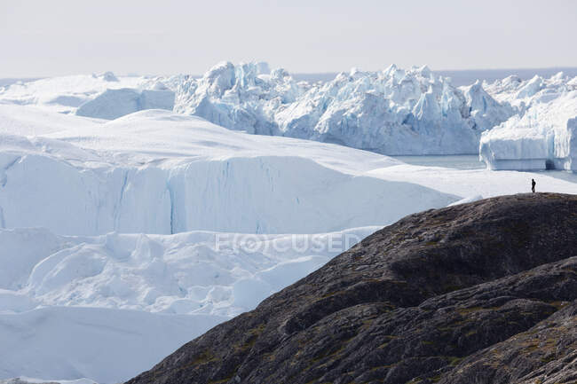 L'uomo sulla scogliera che domina maestosi ghiacciai polari Groenlandia — Foto stock