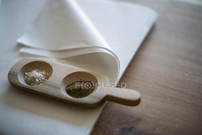Gourmet salt and pepper in wooden tray on tissue paper — Stock Photo