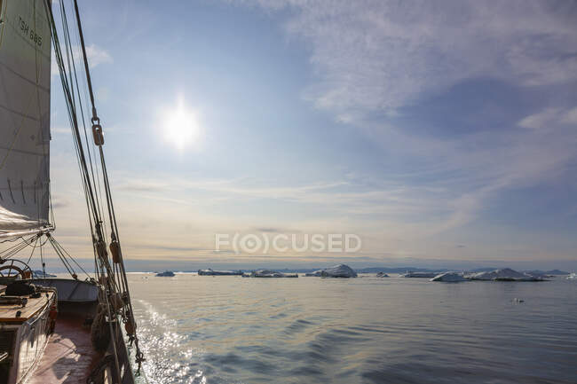 Barco navegando hacia el derretimiento del hielo en el soleado y tranquilo Océano Atlántico Groenlandia - foto de stock