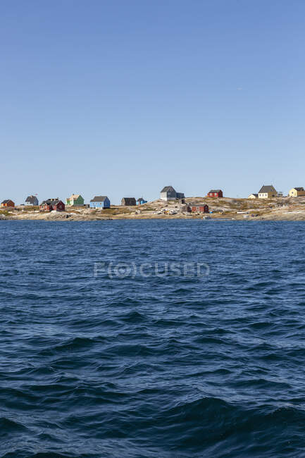 Houses on sunny remote ocean coastline Disko Bay West Greenland — Stock Photo