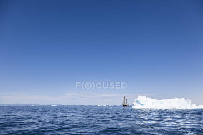 Ship sailing behind iceberg on sunny blue Atlantic Ocean Greenland — Stock Photo