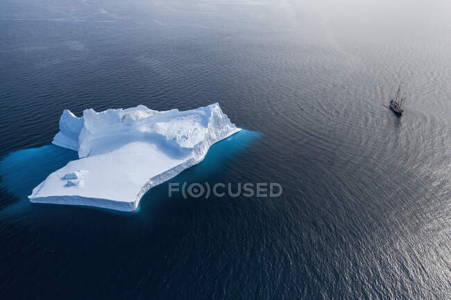 Ship sailing past majestic iceberg formation on blue Atlantic Ocean Greenland — Stock Photo
