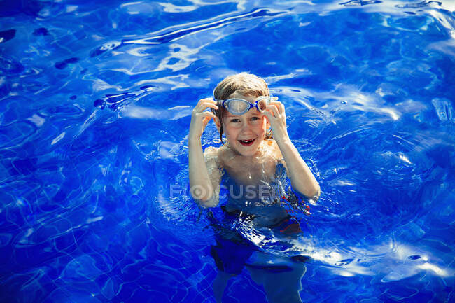 Portrait garçon heureux nageant dans le livre de natation bleu ensoleillé — Photo de stock