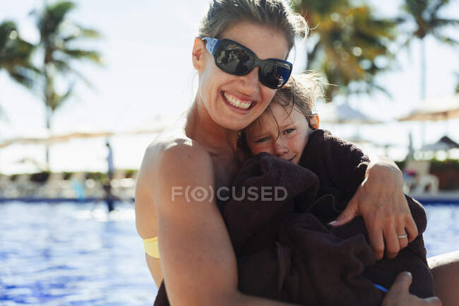Портретна мати тримає сина, загорнутого в рушник на сонячному березі — стокове фото