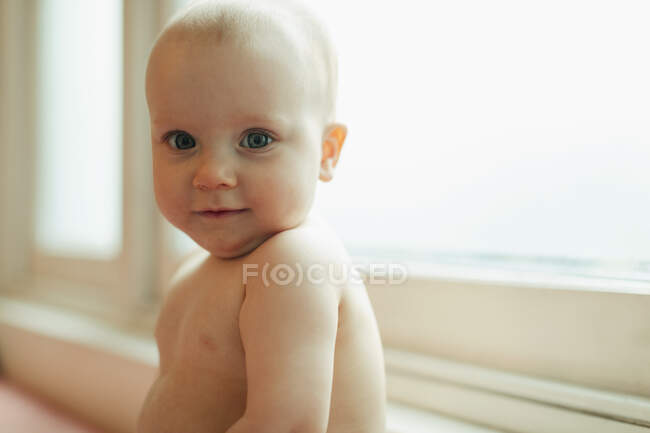 Portrait mignon bébé fille dans la fenêtre — Photo de stock