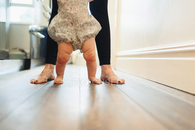 Мати з низьким розділом допомагає доньці ходити в коридорі — стокове фото