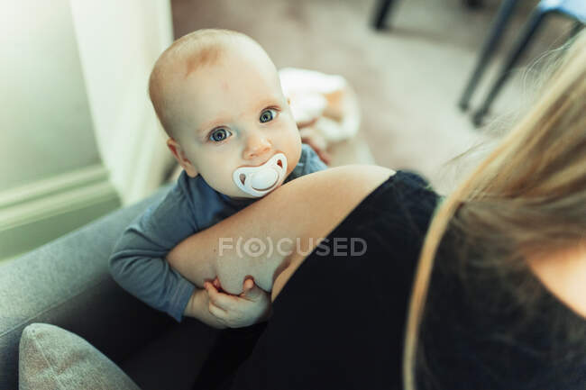 Ritratto carino bambina con pacificatore in braccio madre — Foto stock