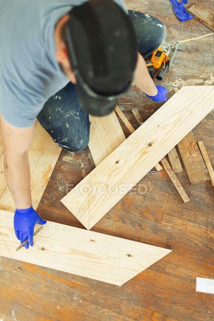 Carpenter marking and cutting floorboards at construction site — Stock Photo