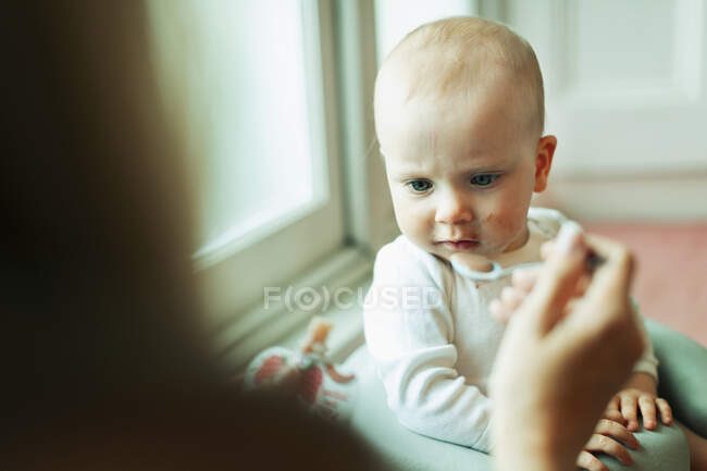 Mother feeding serious baby daughter — Stock Photo