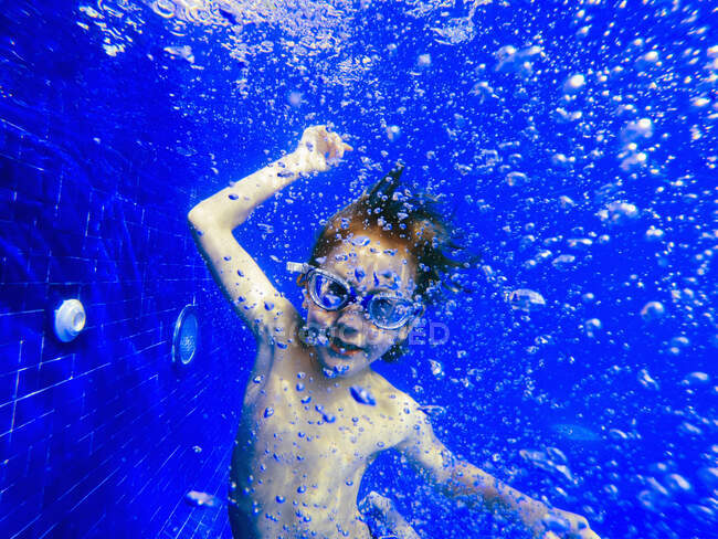 Retrato menino brincalhão nadando debaixo d 'água na piscina azul — Fotografia de Stock