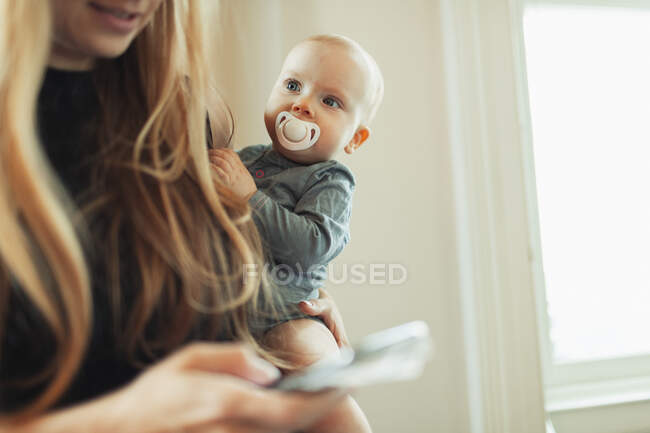 Cute baby girl with pacifier in mother arms — Stock Photo