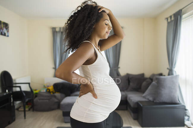 Уставшая молодая беременная женщина в гостиной — стоковое фото