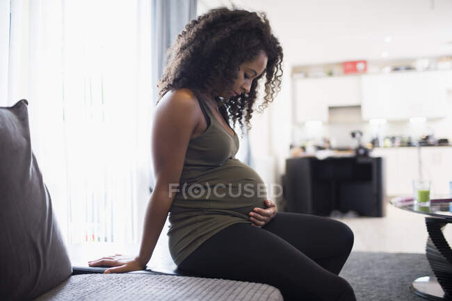 Heitere junge schwangere Frau berührt Bauch — Stockfoto