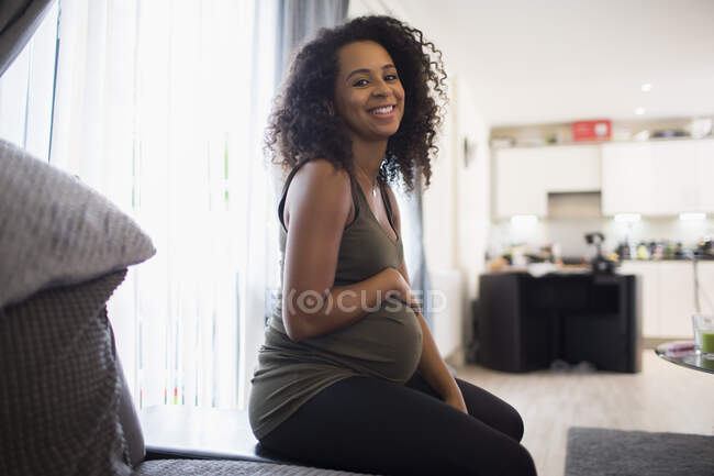 Portrait heureuse jeune femme enceinte frottant l'estomac — Photo de stock