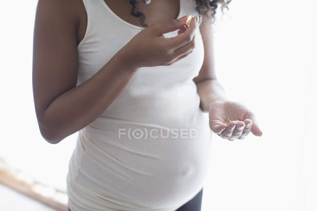 Acercamiento embarazada mujer joven tomando vitaminas prenatales - foto de stock