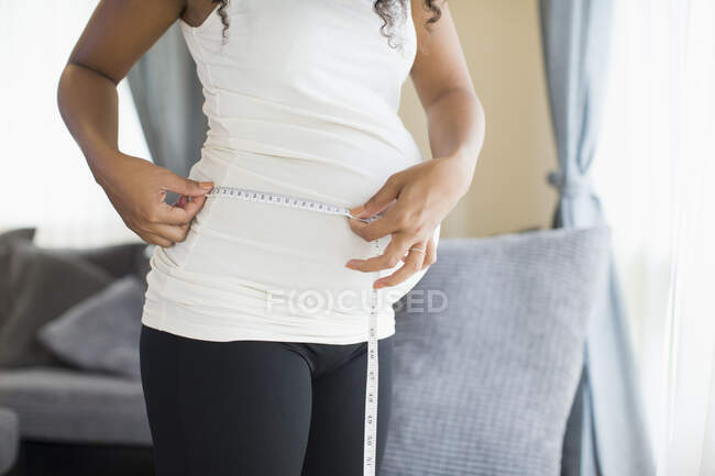 Mujer embarazada midiendo el estómago con cinta métrica - foto de stock