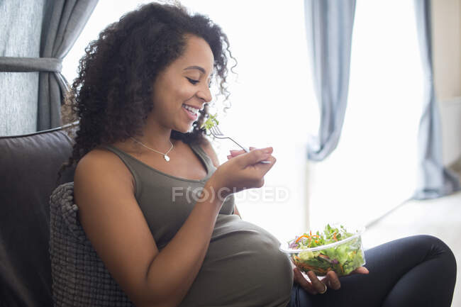 Happy young pregnant woman eating salad — Stock Photo