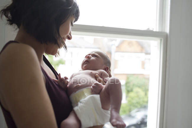 Mère tenant bébé nouveau-né mignon garçon à la fenêtre — Photo de stock