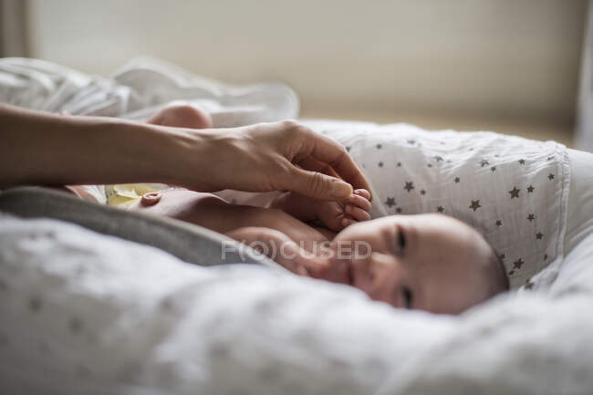 Mother touching innocent newborn baby boy in bassinet — Stock Photo