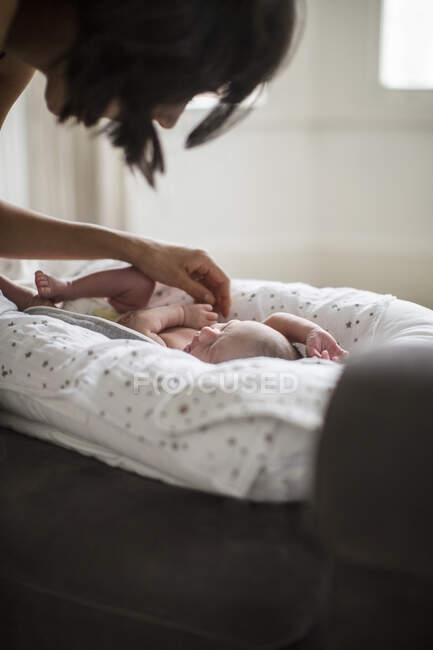 Mãe assistindo bonito bebê recém-nascido filho em bassinet — Fotografia de Stock