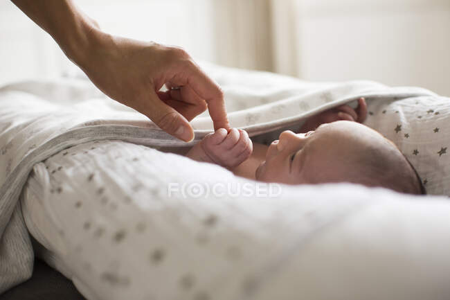 Madre che si tiene per mano con il neonato in culla — Foto stock